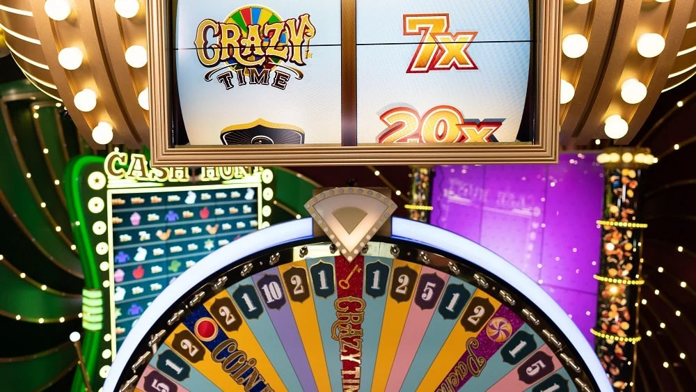 Parte superior da roda Crazy Time com destaque para o multiplicador de bônus na tela acima, exibindo valores de 7x e 20x. Ao fundo, painel 'Cash Hunt' e iluminação vibrante do estúdio com decoração roxa e dourada