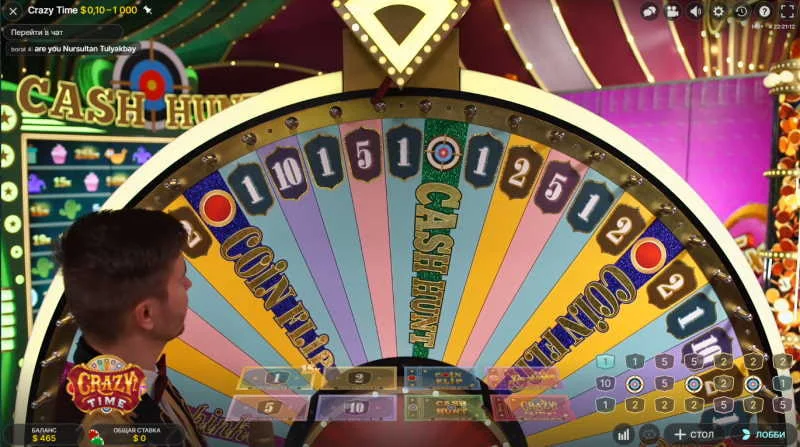 Apresentador ao vivo diante da roda giratória do Crazy Time com destaque para os segmentos 'Coin Flip' e 'Cash Hunt', interface interativa visível com apostas, multiplicadores e chat no canto superior esquerdo.